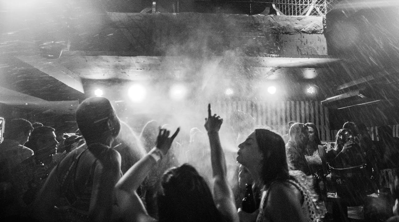services-02 A dynamic black and white image captures a vibrant nightclub crowd dancing amidst smoke and lights.
